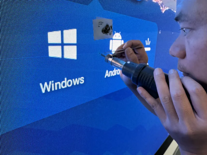 Techniker repariert einzelne Pixel am LED Display mit Präzisionswerkzeug